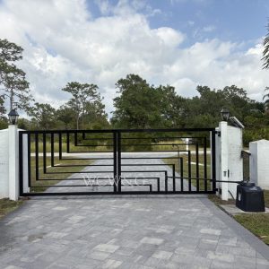 Modern black metal driveway gate with geometric design, flanked by white pillars and black fence, under a cloudy sky.