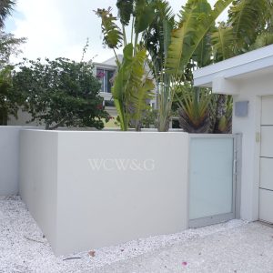 Modern white exterior wall with frosted glass gate, tropical plants, and “WCW&G” lettering.